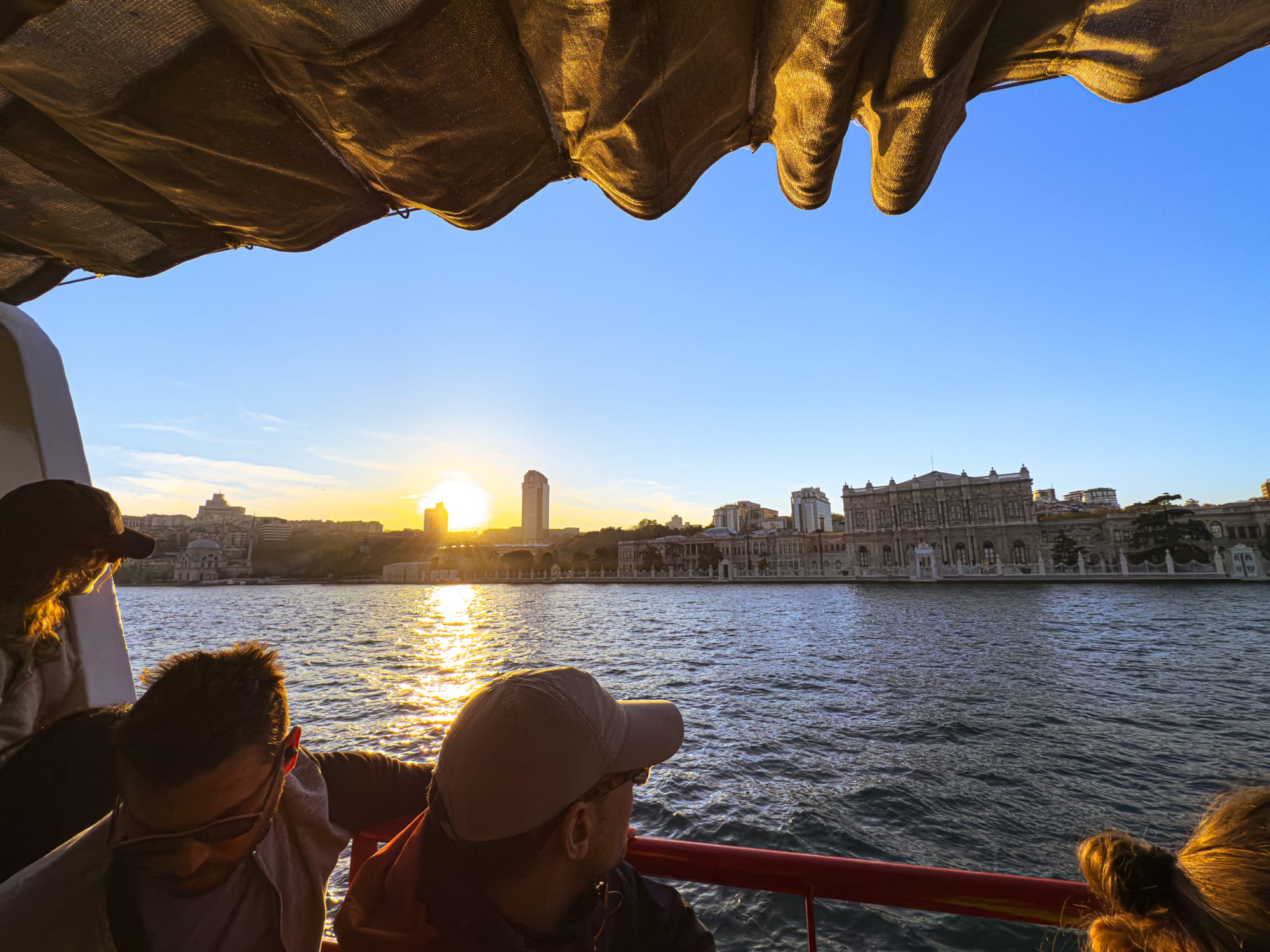 People watching the sunset from a Bosphorus cruise boat, with Dolmabahçe Palace and the Istanbul skyline in view