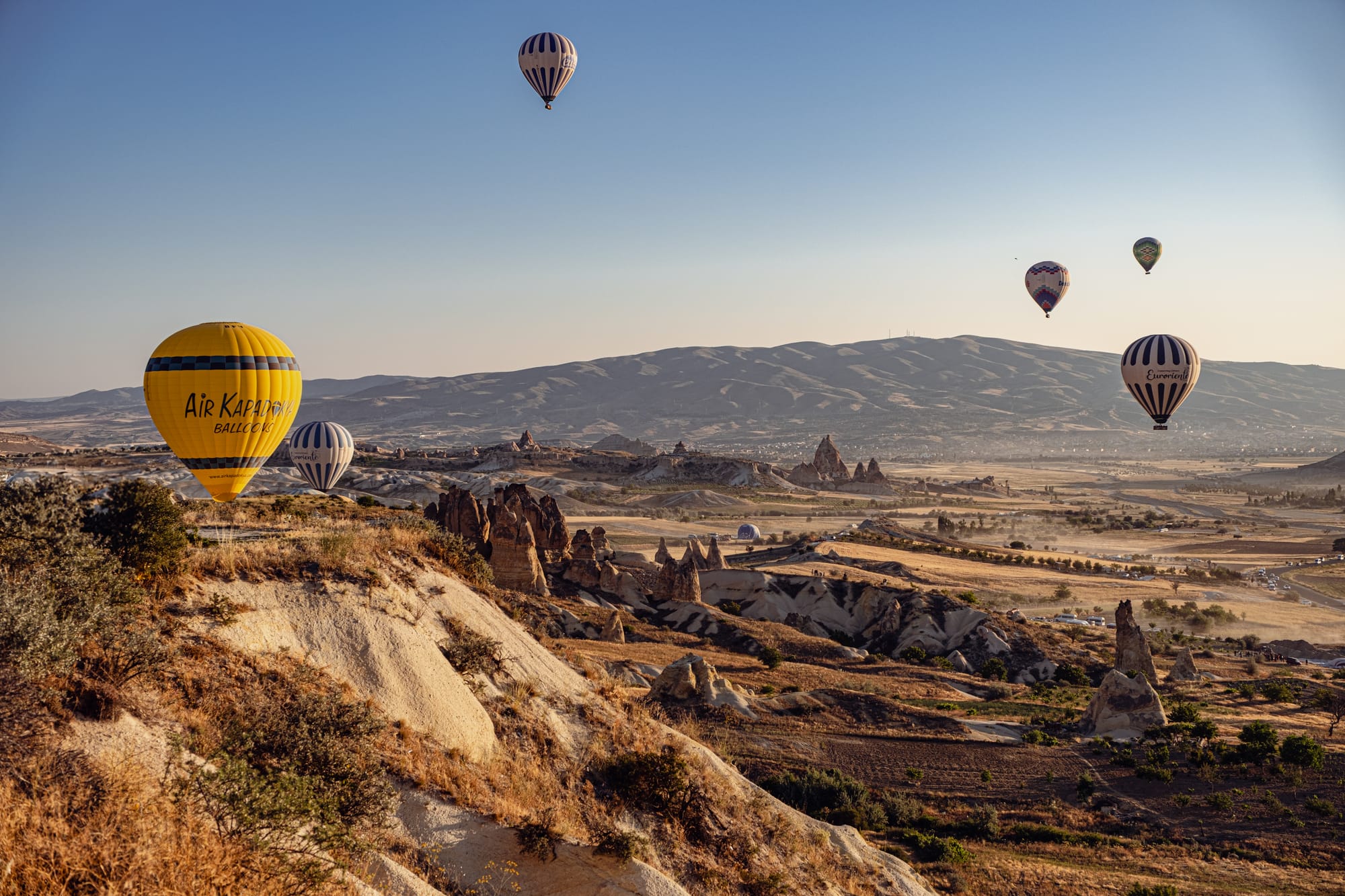 Hot air balloons drift above the valleys of Cappadocia, Turkey, in the golden light of morning
