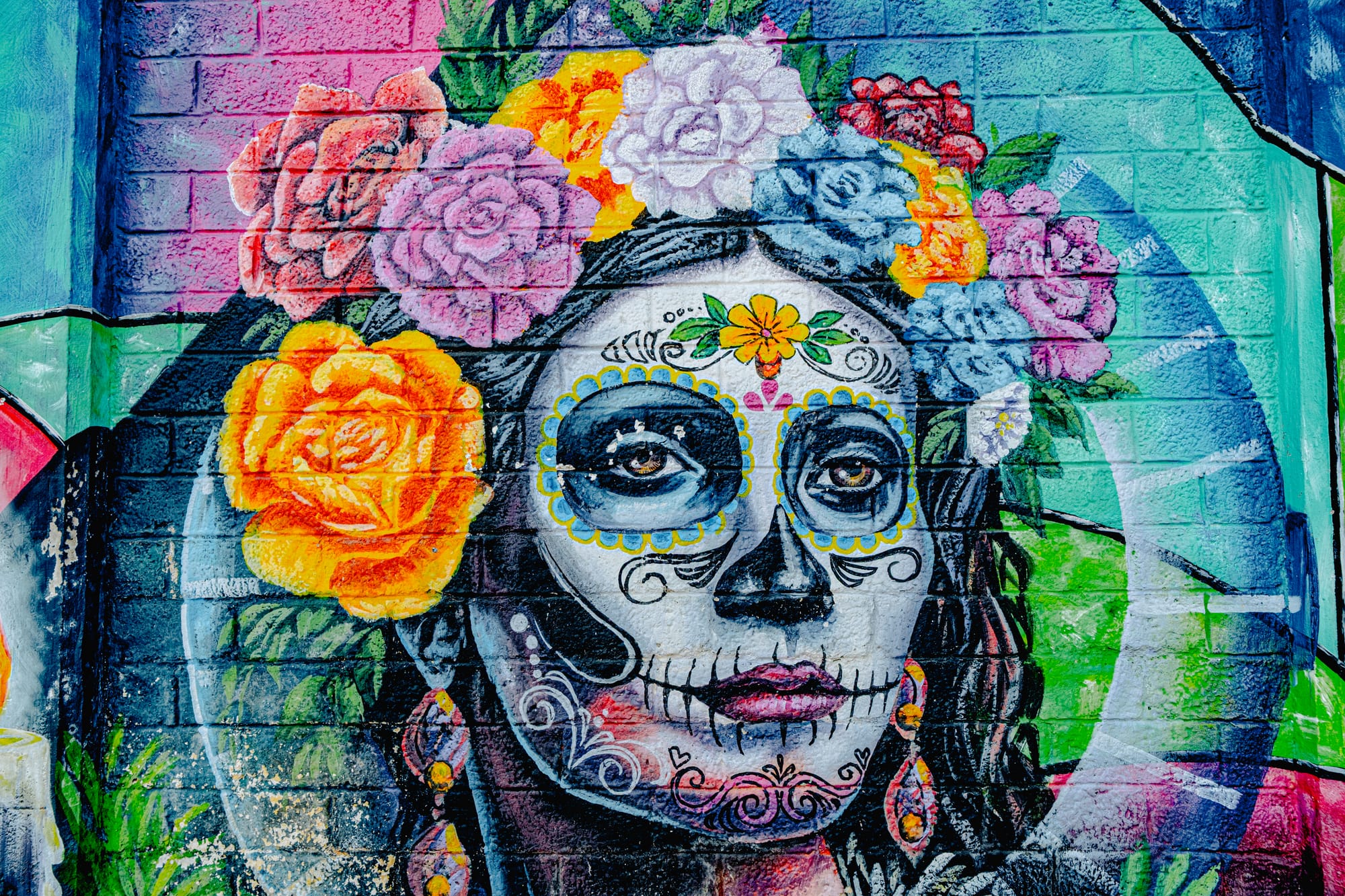 Close-up of a mural in San Cristóbal de las Casas depicting La Catrina’s face adorned with intricate sugar skull makeup and surrounded by colorful roses, representing beauty, remembrance, and the enduring spirit of Día de los Muertos