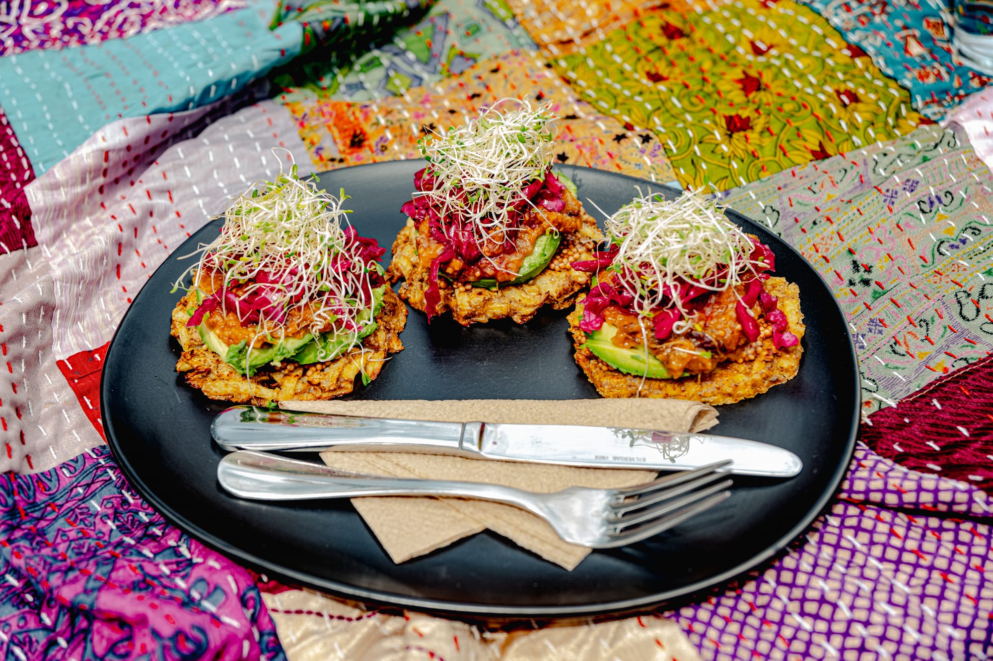 Vegan hashbrowns from Inina in San Cristóbal de las Casas topped with avocado, marinated vegetables, and fresh sprouts on a black plate