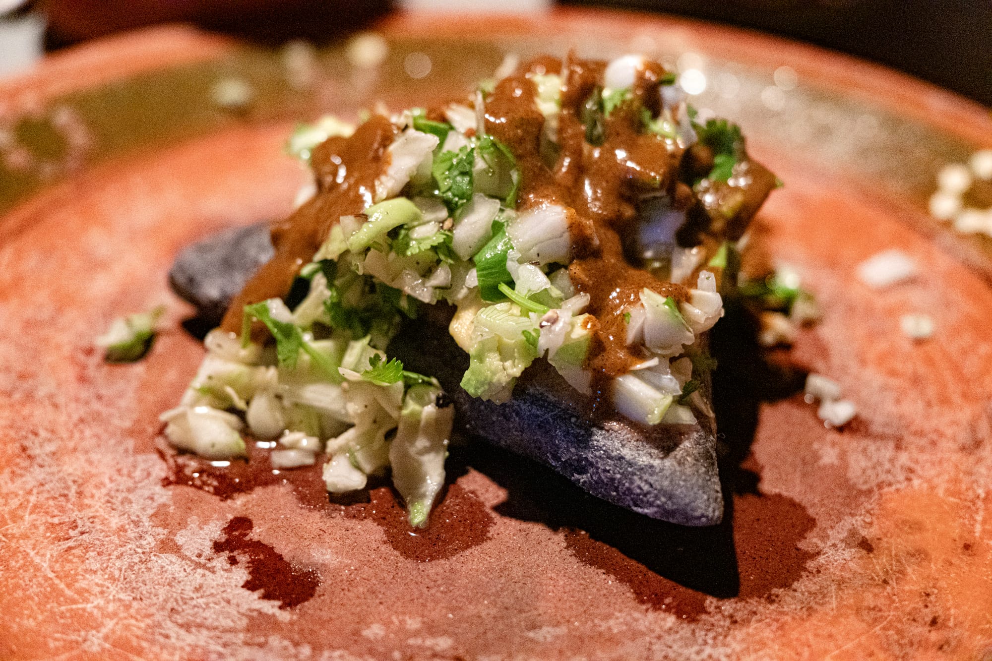 A vegan tetela from Comal in San Cristóbal de las Casas, filled with vegetables and topped with cabbage, cilantro, and a savory mole-style sauce