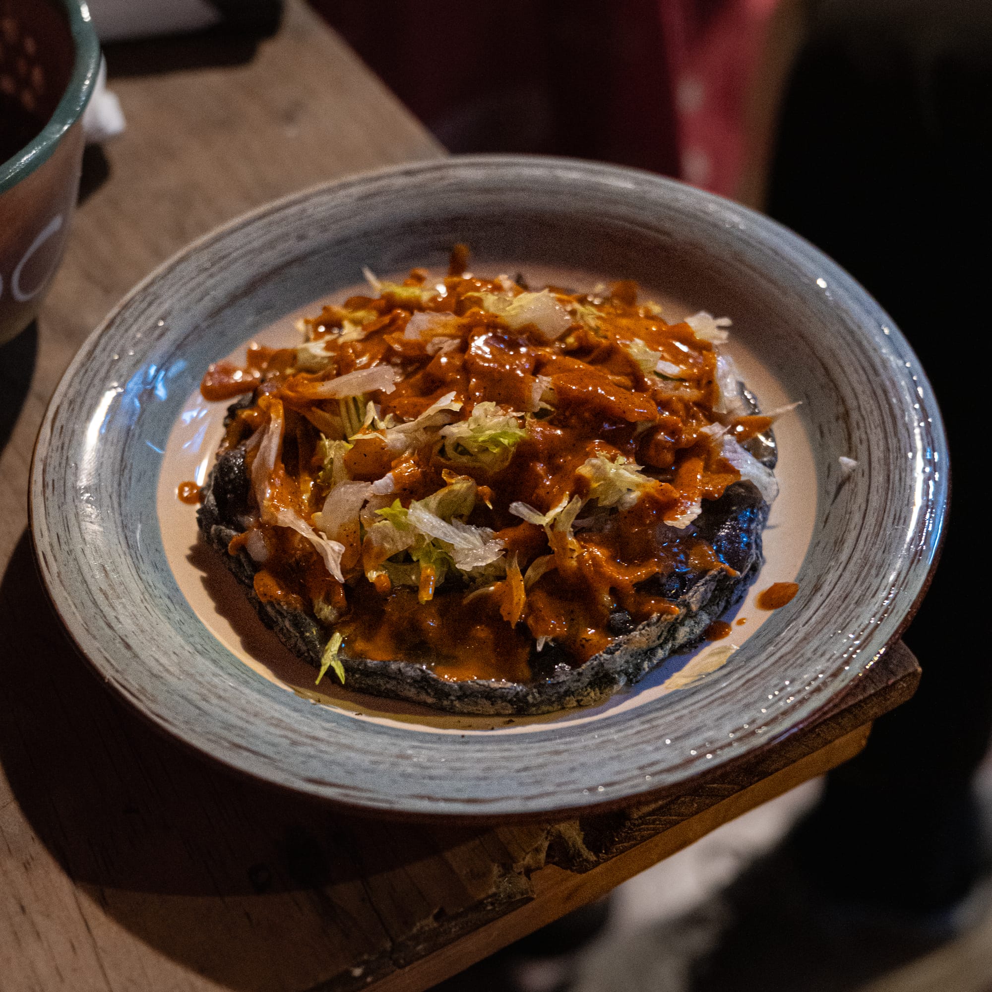 A vegan picadita from Comal in San Cristóbal de las Casas, made with a blue corn base topped with lettuce and a rich red salsa