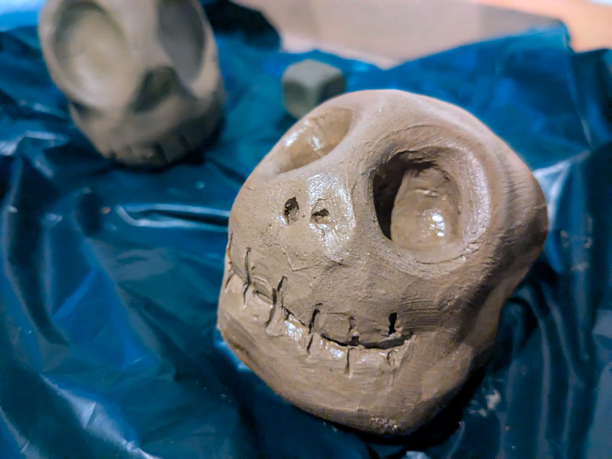 Handmade clay skull created during Día de Muertos preparations at Co404 in San Cristóbal de las Casas, Chiapas, Mexico, wet clay calavera sculpture before painting, traditional Day of the Dead craft activity, communal altar preparation process