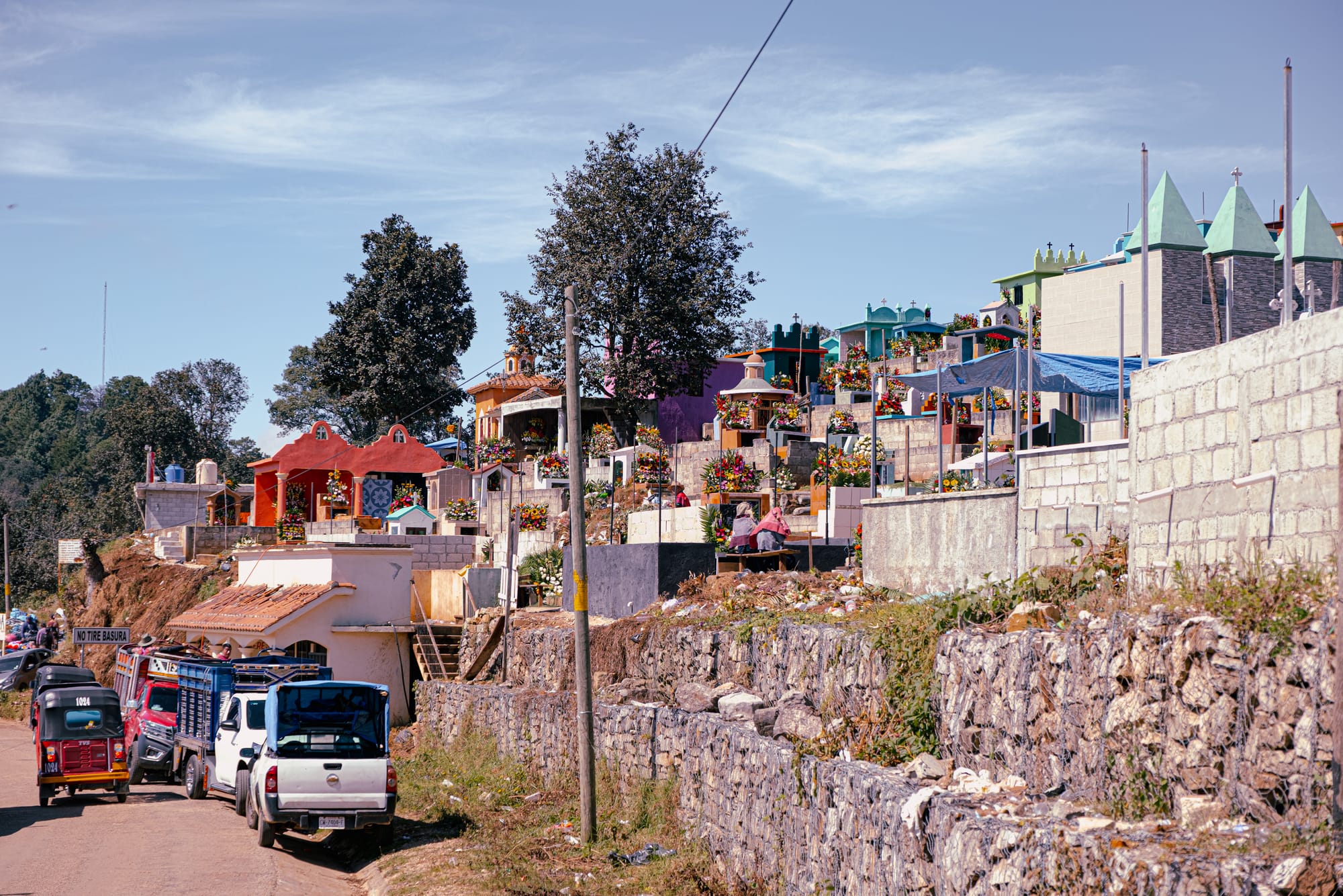 Día de Muertos at Zinacantán Cemetery in Zinacantán, Chiapas, Mexico, panoramic view of hillside cemetery with colorful above ground tombs and flower covered graves, mountain setting above San Cristóbal de las Casas, floral arrangements defining Day of the Dead traditions in a town known for flower cultivation