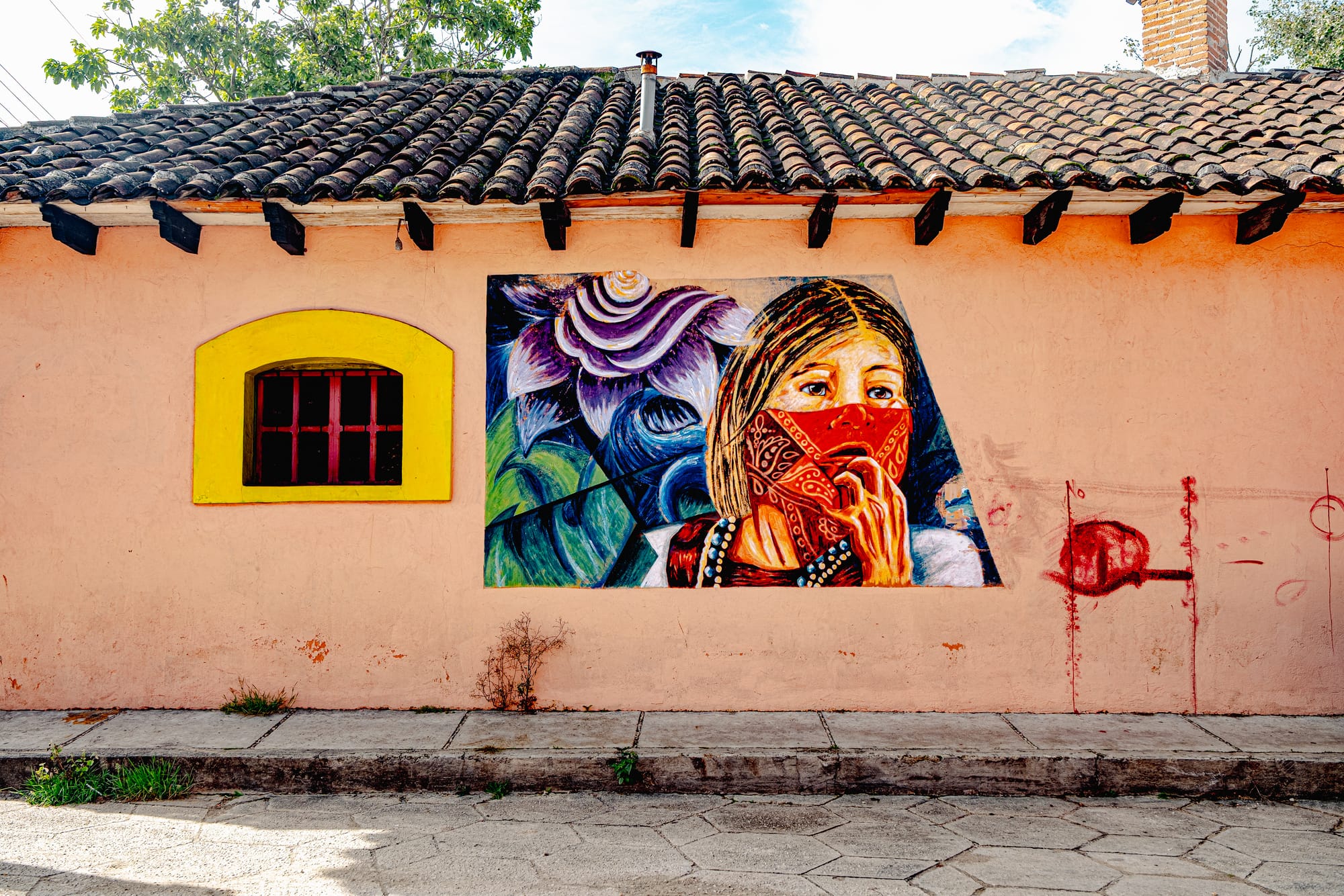Digital nomad life in San Cristóbal de las Casas Mexico, indigenous street art mural in the Chiapas Highlands, portrait of indigenous woman painted on colonial wall, creative culture and political expression in San Cristóbal, walkable historic neighborhood, digital nomad and remote work destination in southern Mexico