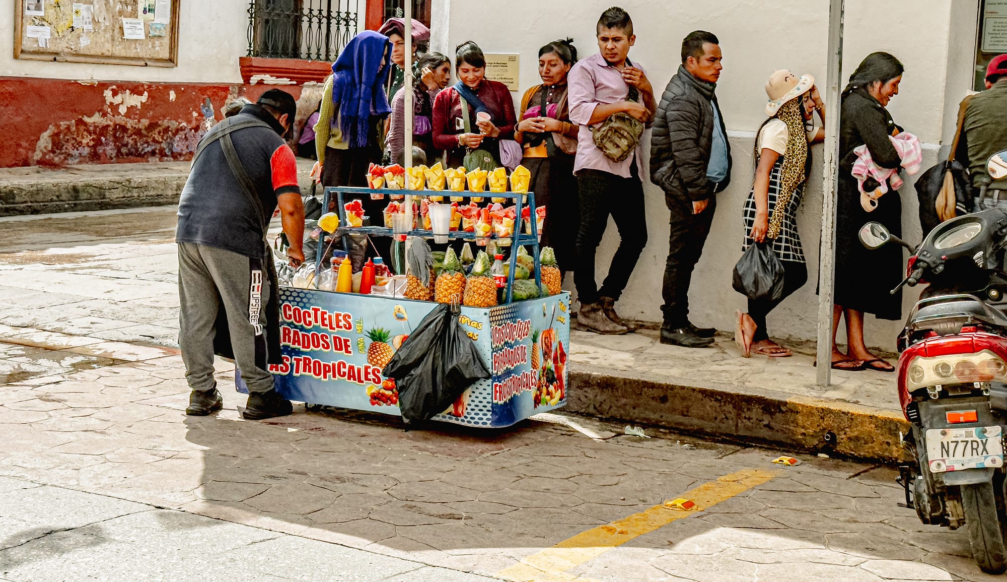 Digital nomad life in San Cristóbal de las Casas Mexico, street fruit vendor selling tropical fruit cups, everyday food culture and informal economy, people gathering around street cart in historic center, walkable city life in the Chiapas Highlands, daily rhythms experienced by digital nomads and remote workers in southern Mexico