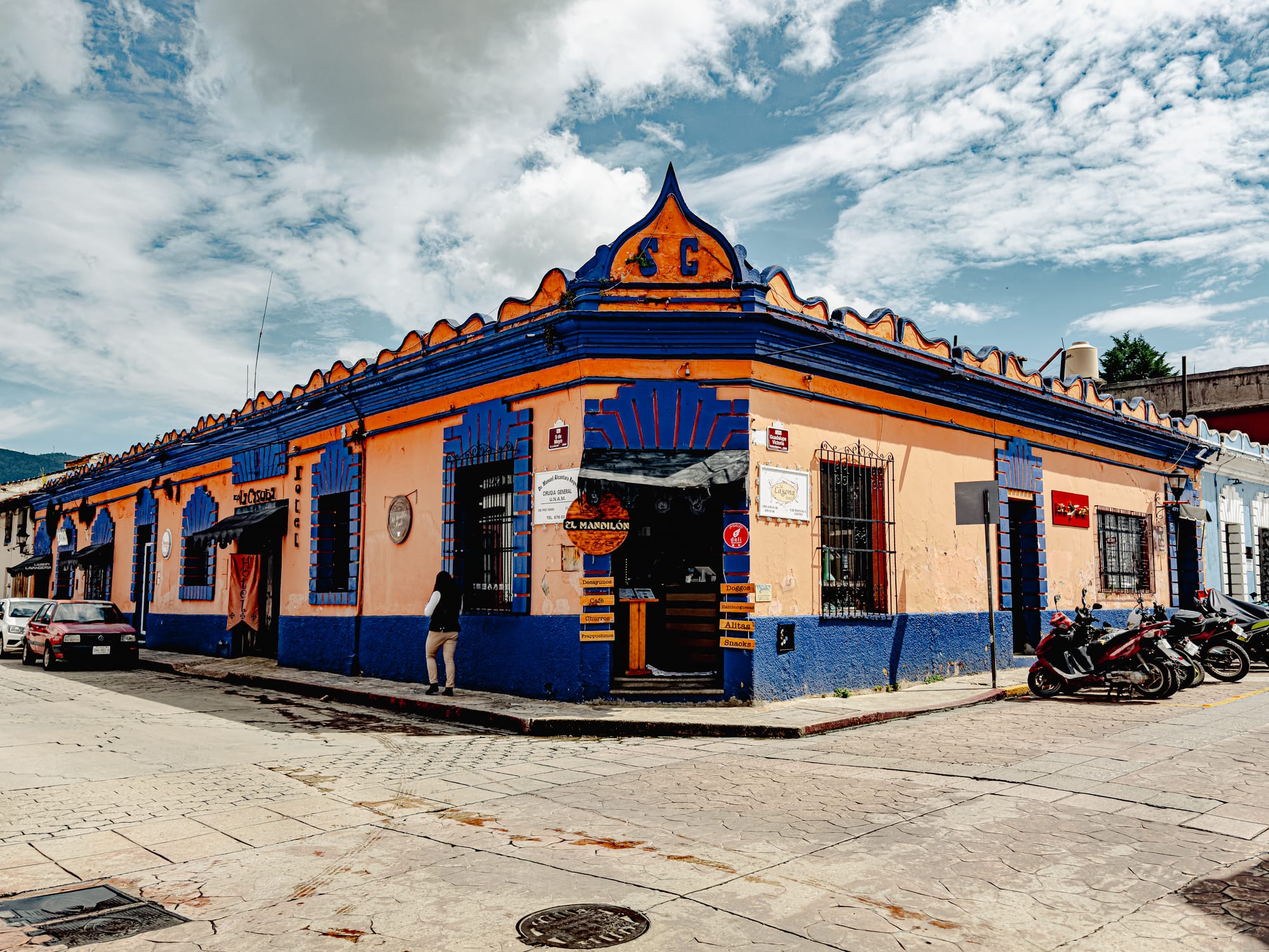 Digital nomad life in San Cristóbal de las Casas Mexico, colorful colonial corner building with café and restaurant, walkable historic street in the Chiapas Highlands, everyday urban scene with local businesses, remote work friendly city atmosphere, lived in streets of southern Mexico