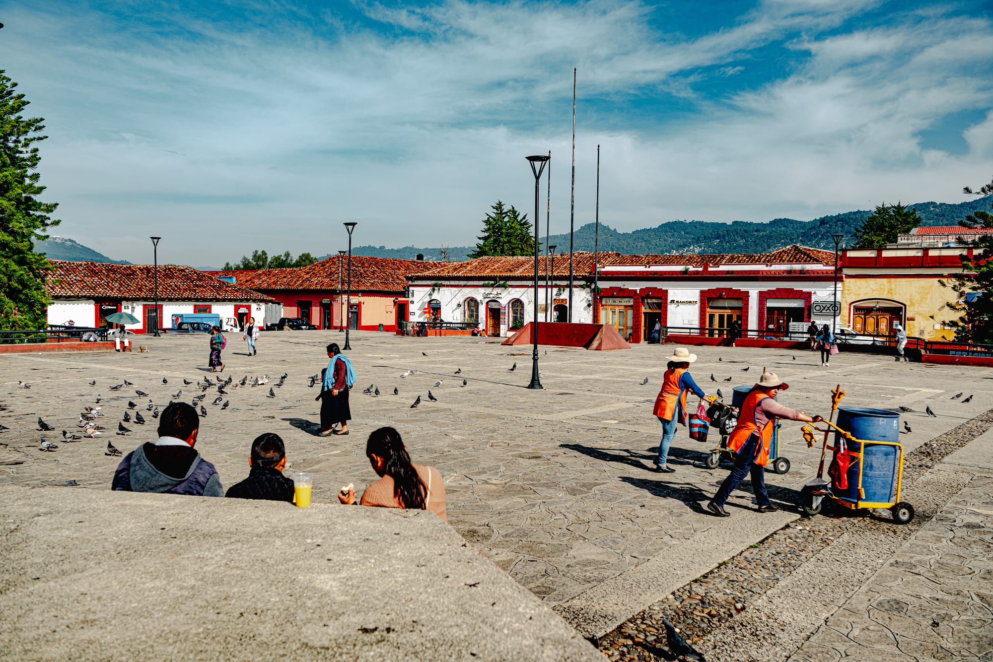 Digital nomad life in San Cristóbal de las Casas Mexico, daily life in a central plaza in the Chiapas Highlands, people sitting and walking through open square, municipal workers cleaning plaza, indigenous town atmosphere, remote work friendly city, affordable digital nomad destination in southern Mexico