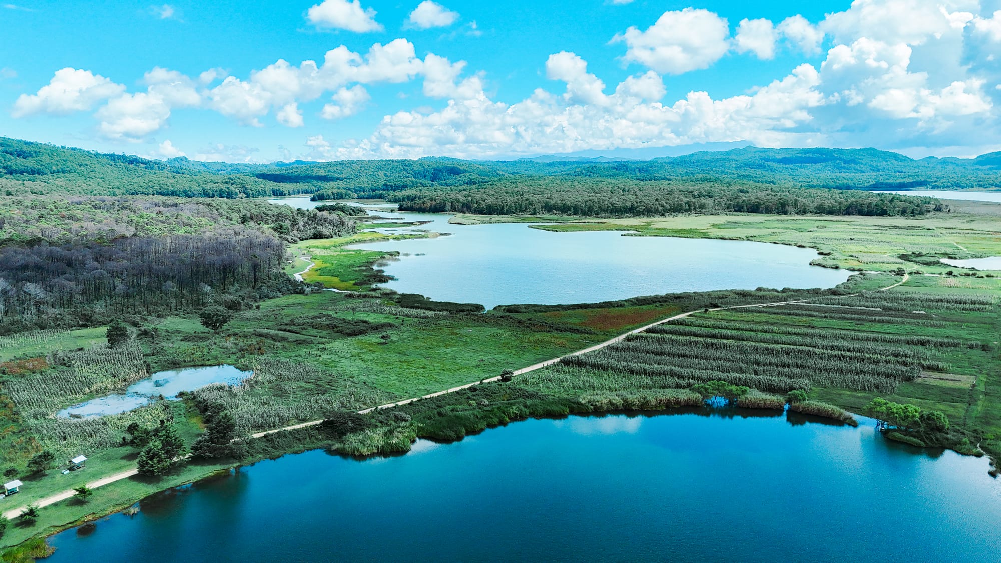 Aerial panorama of Montebello Lakes in Chiapas showing expansive turquoise lakes, wetlands, and forested mountains stretching toward the horizon near the Guatemala border