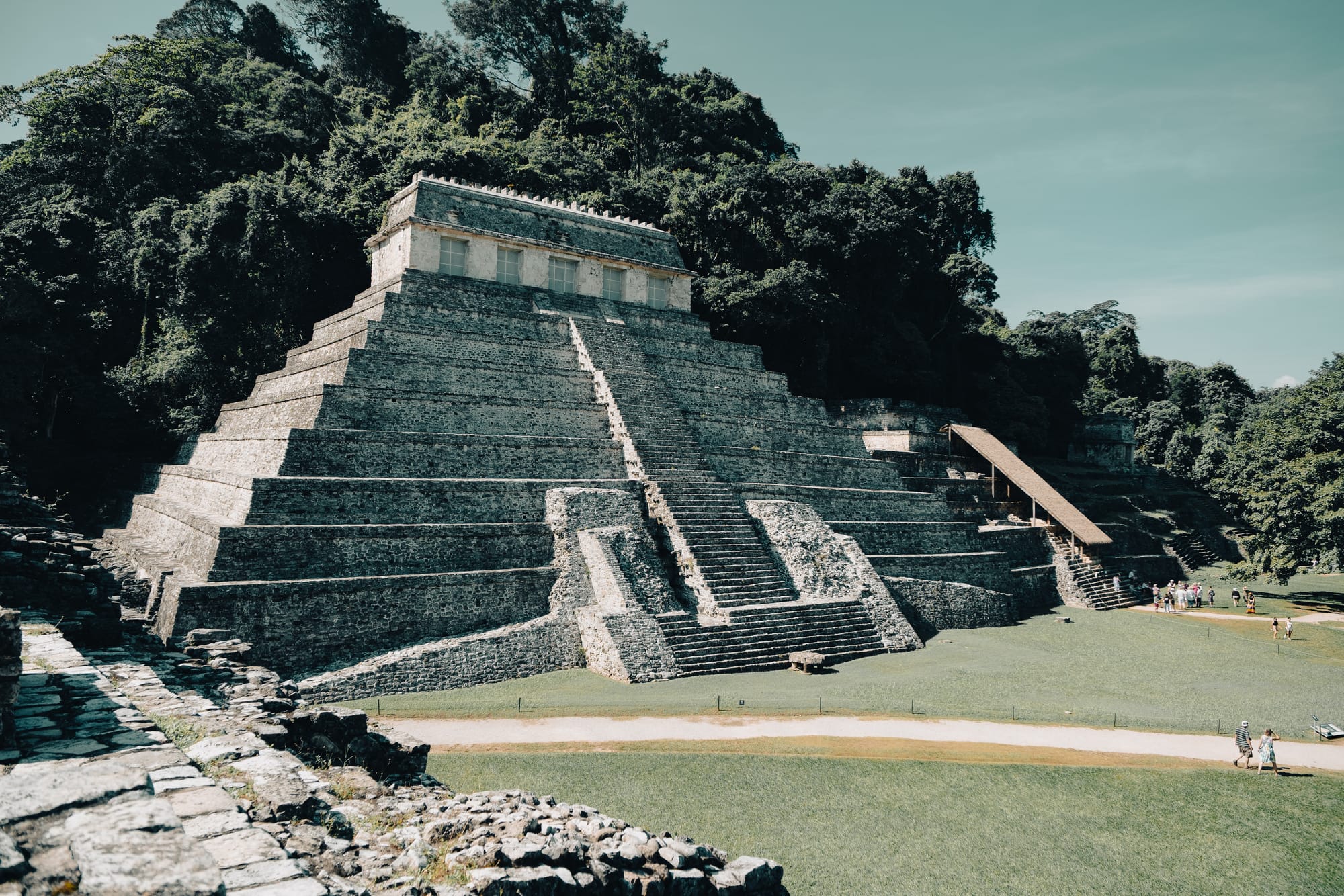 Temple of the Inscriptions at Palenque Mayan ruins seen from an elevated viewpoint, large stepped pyramid dominating the Palenque archaeological site in Chiapas Mexico, iconic Maya temple built for Pakal the Great surrounded by dense jungle, visitors exploring UNESCO World Heritage Mayan ruins near San Cristóbal de las Casas