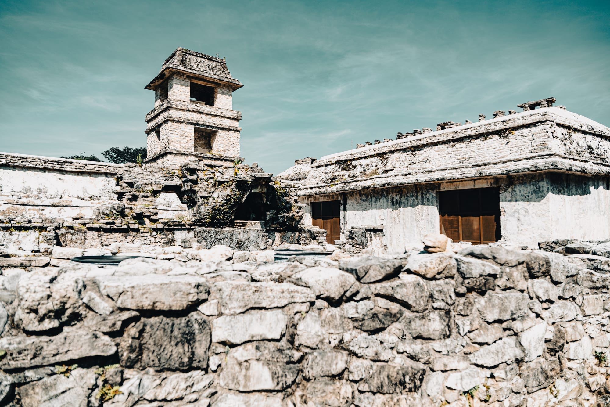Palenque Palace complex tower and surrounding stone buildings at Palenque Mayan ruins in Chiapas Mexico, ancient Maya administrative architecture with elevated tower and courtyards, iconic Palenque archaeological site surrounded by jungle forest near San Cristóbal de las Casas