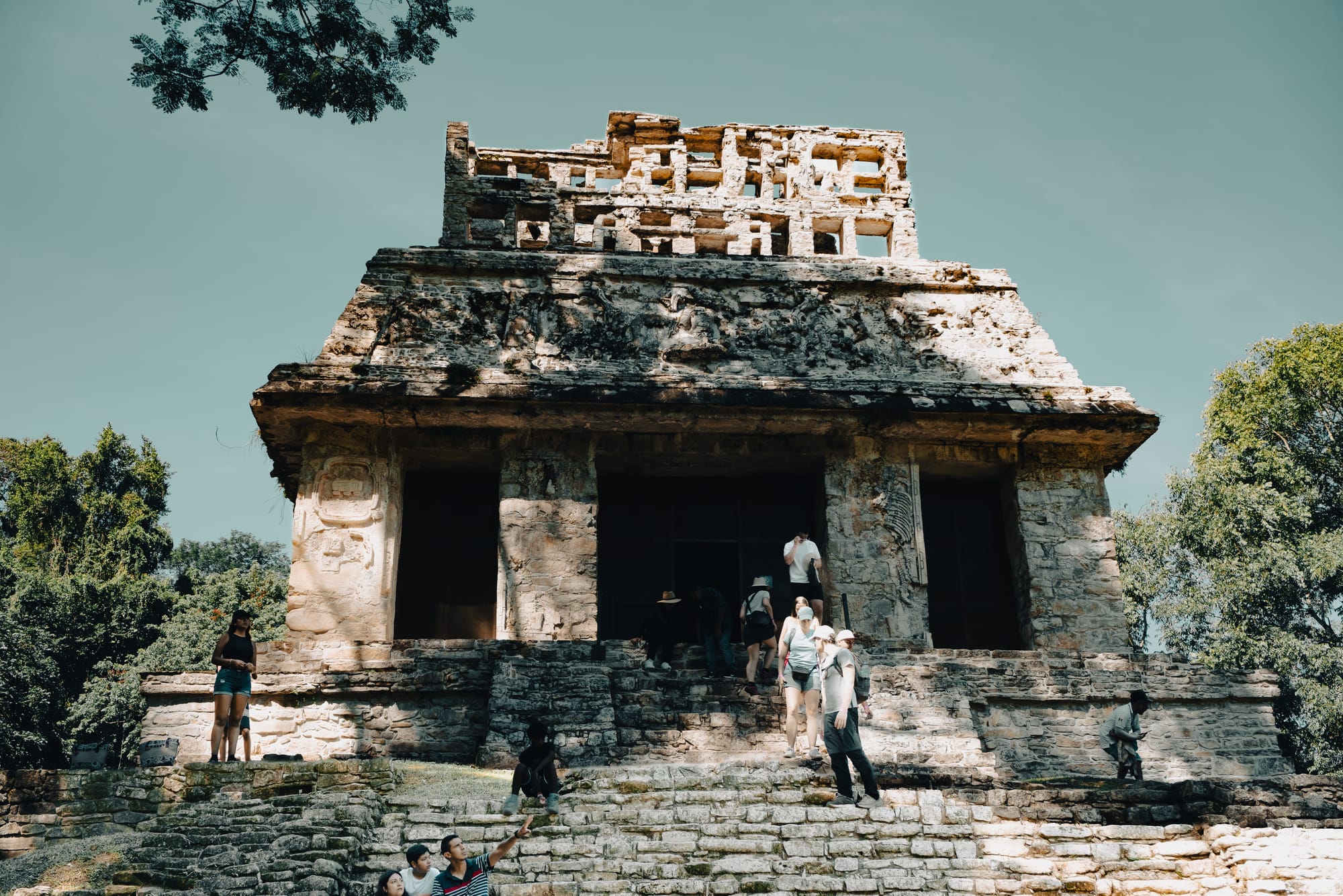 Palenque Mayan ruins Temple of the Cross with visitors climbing stone steps, ancient Maya ceremonial temple at Palenque archaeological site in Chiapas Mexico, iconic Palenque structure with carved reliefs and jungle backdrop, Mayan ruins near San Cristóbal de las Casas showing scale and architectural detail