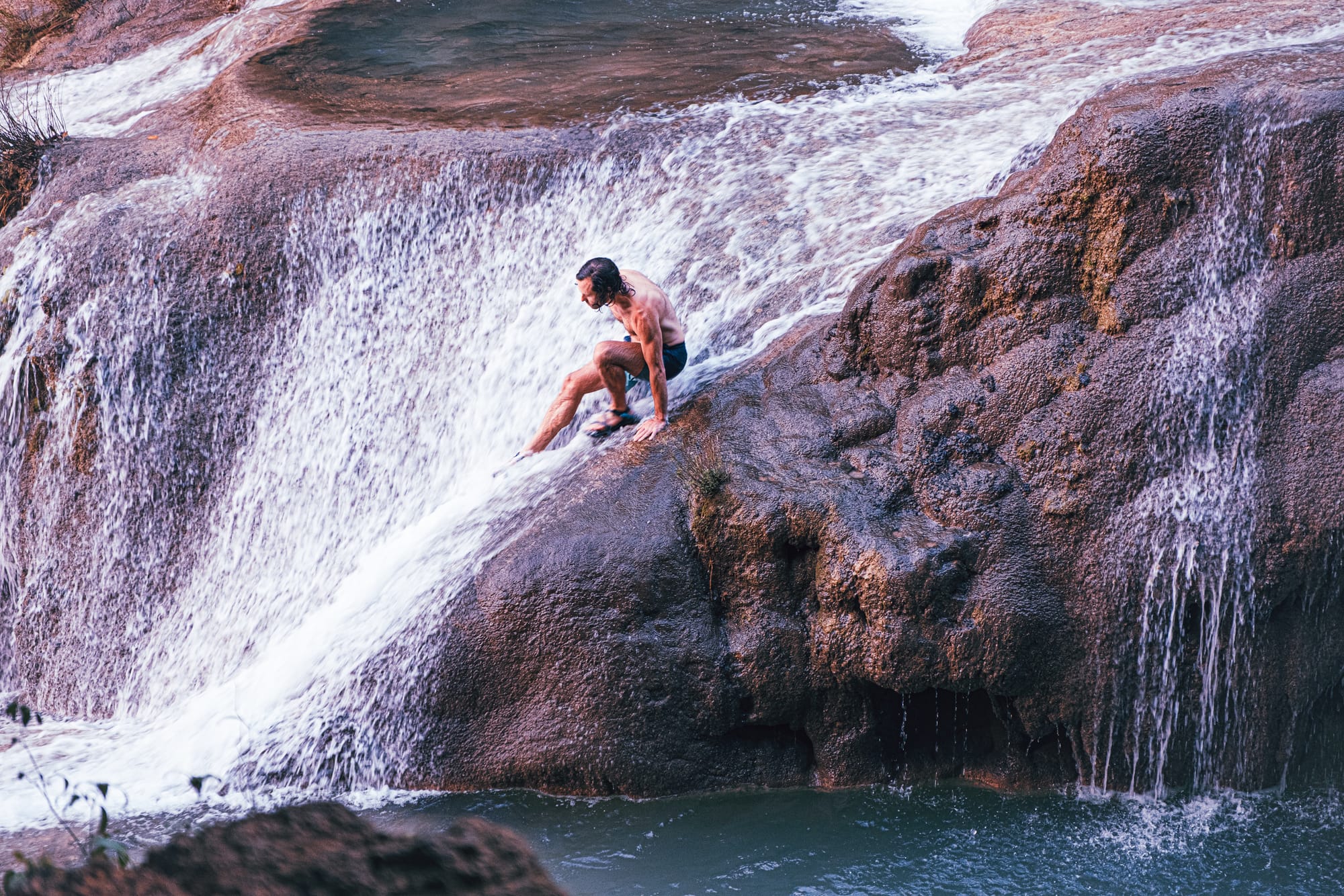 Cascadas Roberto Barrios waterfalls near Palenque, Chiapas, Mexico, person walking on sloping limestone waterfall, water flowing over rock shelves, walkable cascades and swimming pools, jungle waterfalls Roberto Barrios day trip from Palenque
