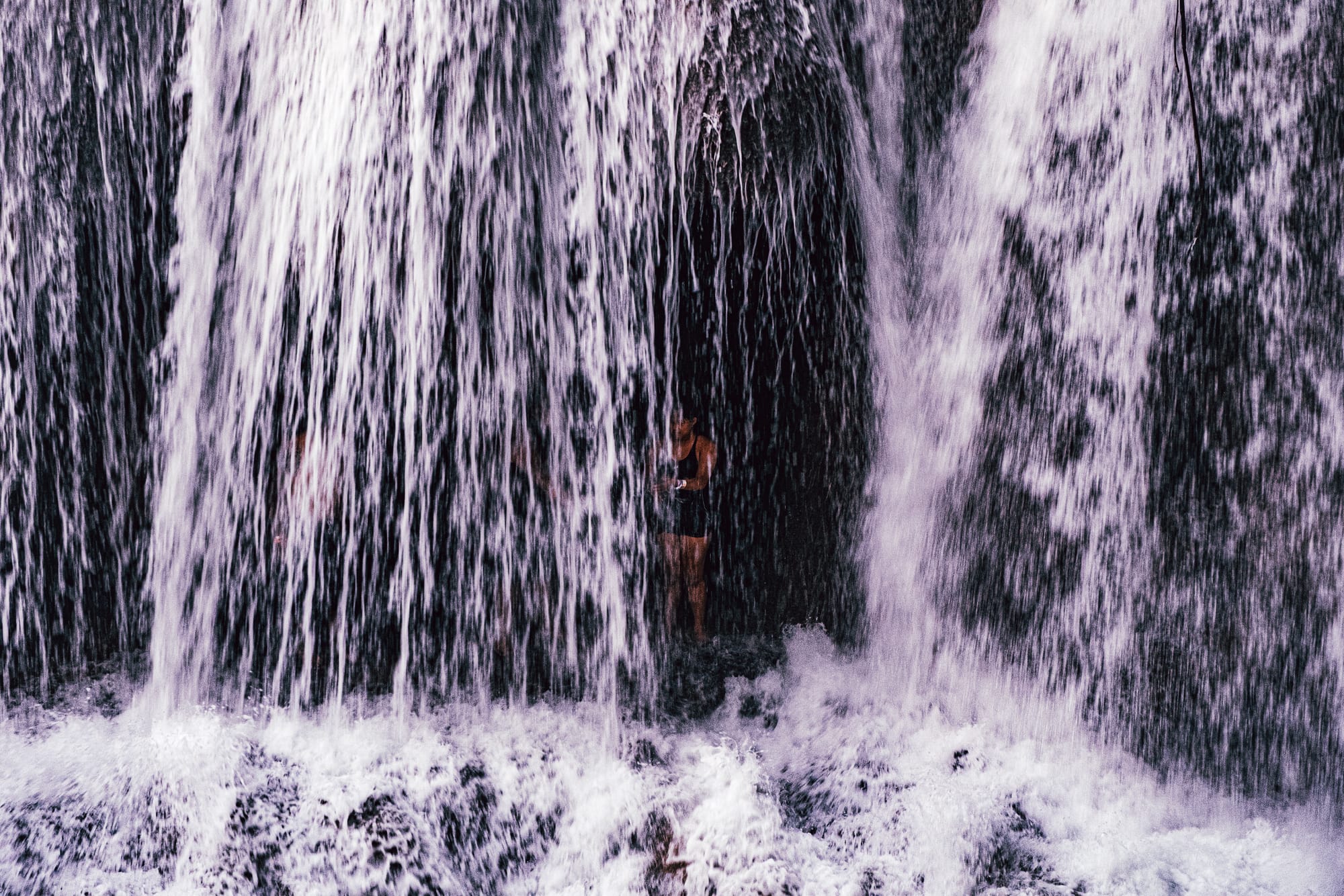 Cascadas Roberto Barrios waterfalls near Palenque, Chiapas, Mexico, person standing behind waterfall curtain, water cascading down limestone rock, walk behind waterfalls experience, jungle waterfalls Roberto Barrios natural pools