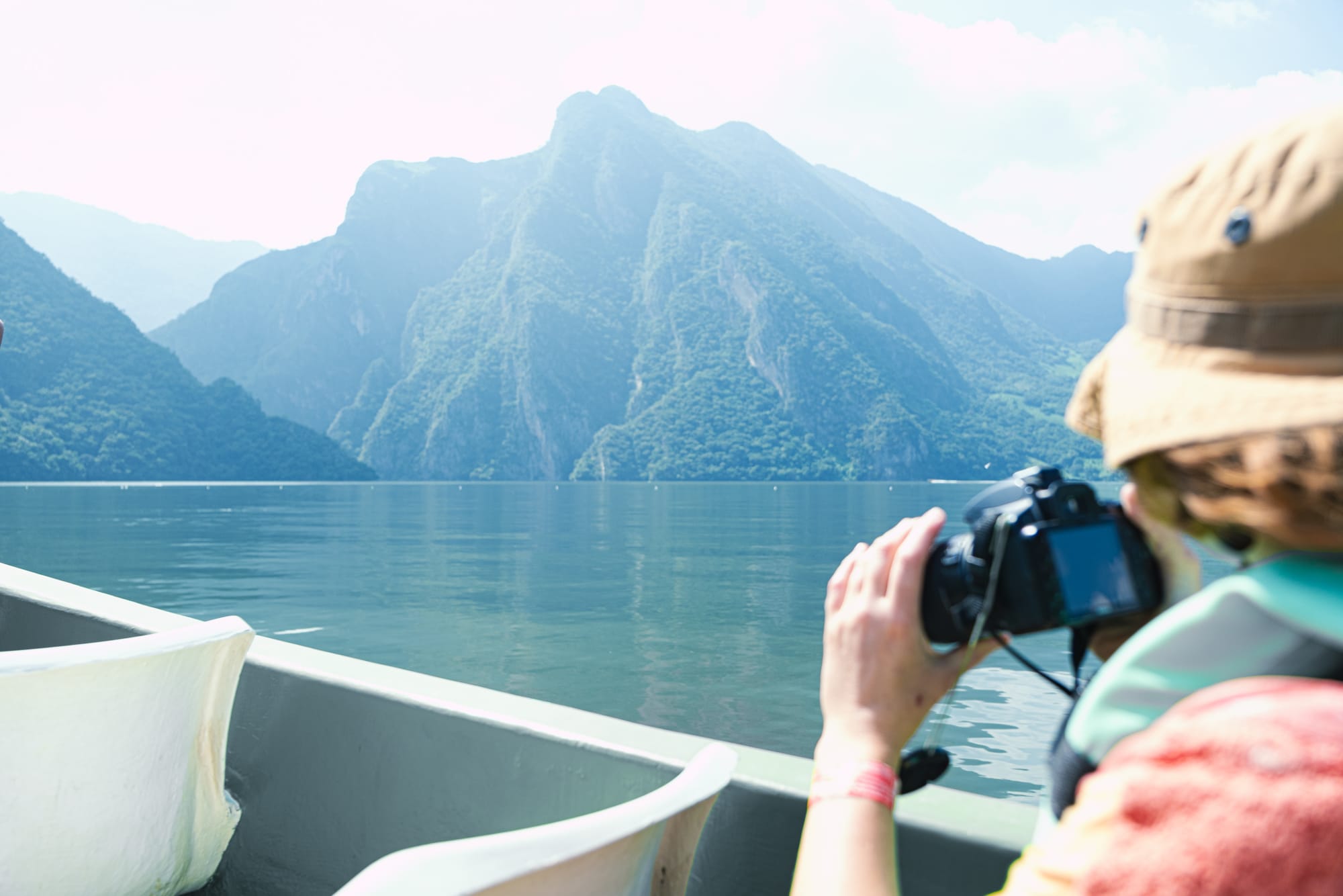 Person photographing the steep green cliffs of Sumidero Canyon from a boat on the Grijalva River during a scenic day trip in Chiapas, Mexico