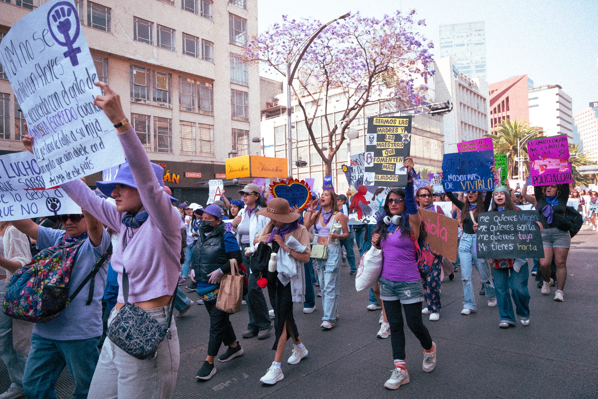Documentary photography of women marching with protest signs during the 8M feminist march in Mexico City
