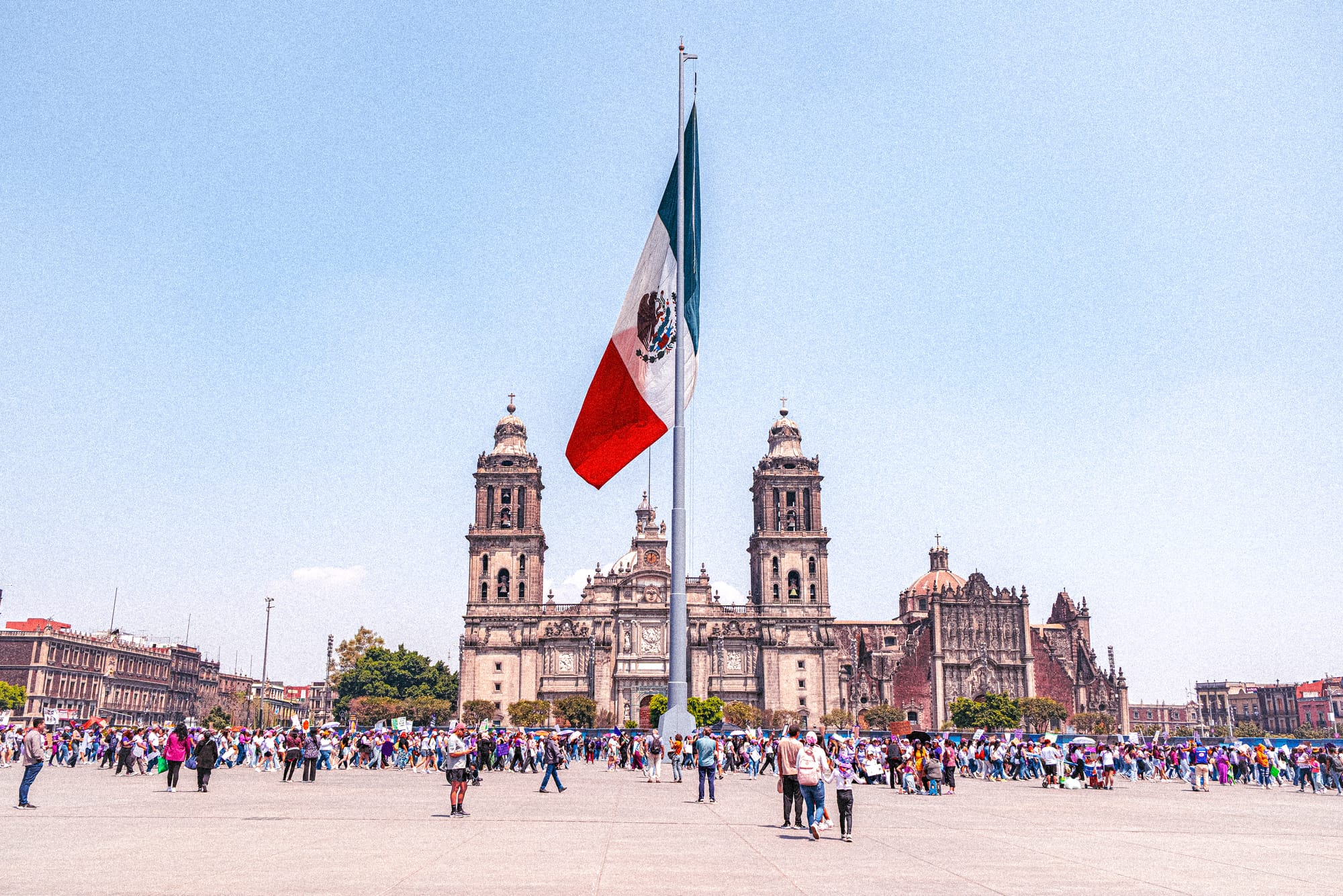 Feminist protesters gathered in the Zócalo during the 8M march in Mexico City with the Metropolitan Cathedral and Mexican flag in the background
