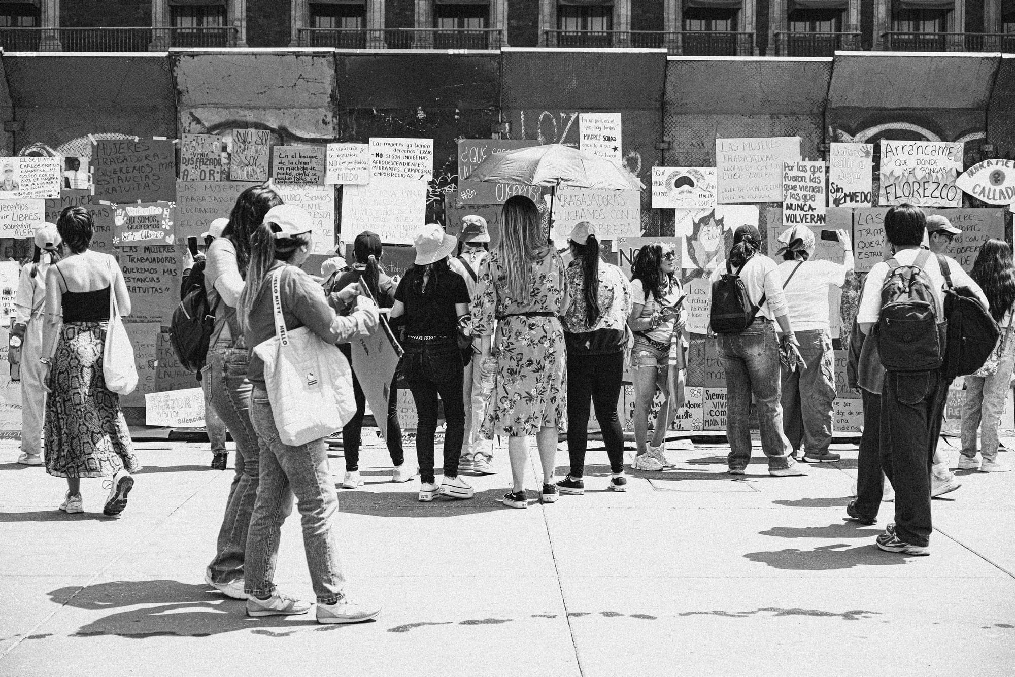 Mujeres observando carteles feministas durante la marcha 8M en Ciudad de México contra el feminicidio y la violencia de género