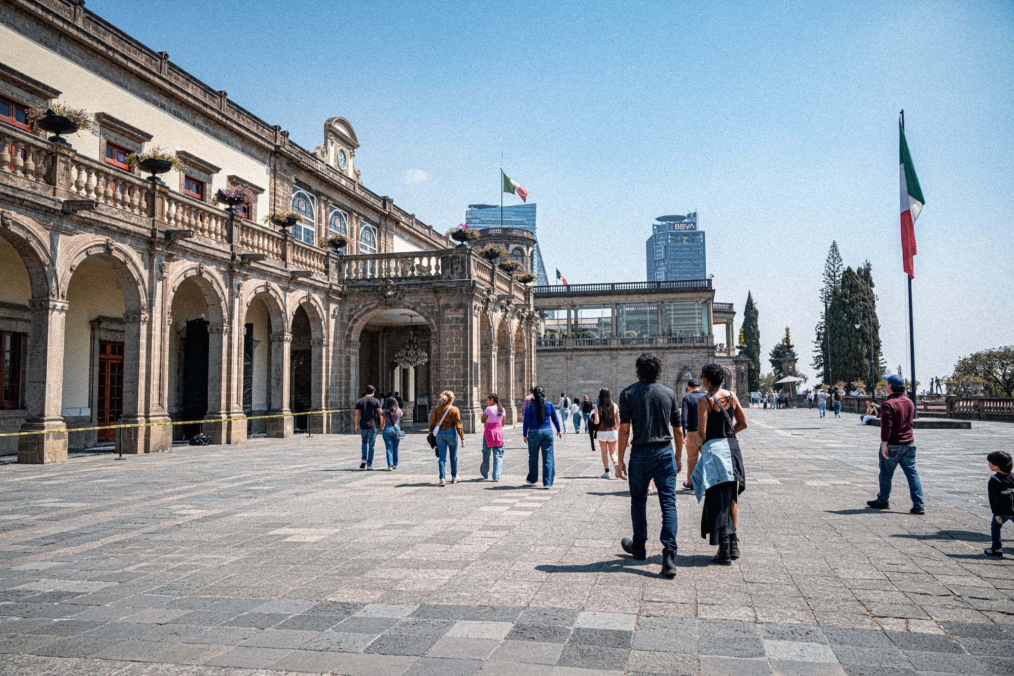 Chapultepec Castle Mexico City terrace with visitors walking near historic arches and Mexican flag