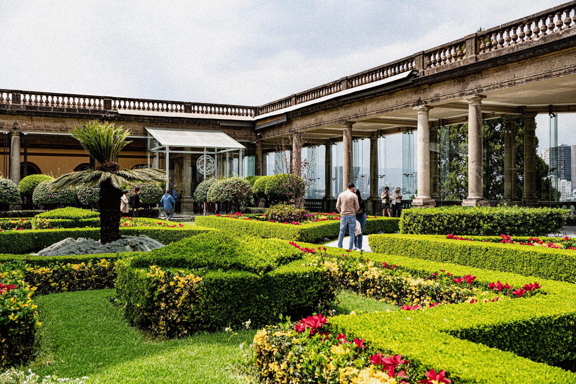 Chapultepec Castle Mexico City gardens with manicured hedges, flowers, and visitors near terrace