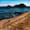 Person walking along a coastal path with Ilhéu de Vila Franca do Campo in the background across the water