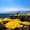 View of Antalya’s dramatic mountain-backed coastline from a beach club filled with bright yellow umbrellas and sun loungers, with people swimming and paddleboarding in the turquoise sea