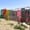 A row of mismatched, hand-painted doors in vibrant colors and weathered textures stands along a dirt hillside in Balat
