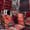 A vibrant display of Turkish rugs in deep reds, oranges, and earthy tones, stacked and draped over walls, doorways, and furniture at Galerie İkman in Göreme