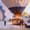 A hot air balloon crew inflating a large black and beige balloon at dawn in Cappadocia, with the basket on a trailer, flames from the burner illuminating the scene