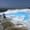 Two visitors walk barefoot along the milky-white travertine terraces of Pamukkale, with brilliant turquoise pools cascading across the landscape