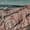 Expansive view of Cappadocia’s Red Valley, featuring dramatic pink and white rock ridges carved by erosion, with distant hills and scattered clouds under a muted sky