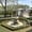 An ornate stone fountain sits at the center of a manicured hexagonal pool, surrounded by trimmed hedges and soft grass in the serene gardens of Topkapi Palace