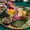 A vibrant dish from Jing Jai Market in Chiang Mai, featuring rice, herbs, edible flowers, shredded vegetables, toasted coconut, and seasonings arranged on a banana leaf
