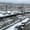 Snow-covered townscape in Bansko with a river lined by stone walls, rocks capped in snow, parked cars blanketed in white, and misty forested mountains in the background